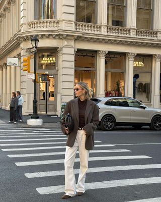 Fashion influencer @Fredrika_ekerot in New York wears an anti-trend outfit with bright creamjeans, an oversized blazer, a brown top and brown suede apartments.