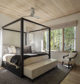 A four poster bed with a black frame in a white bedroom