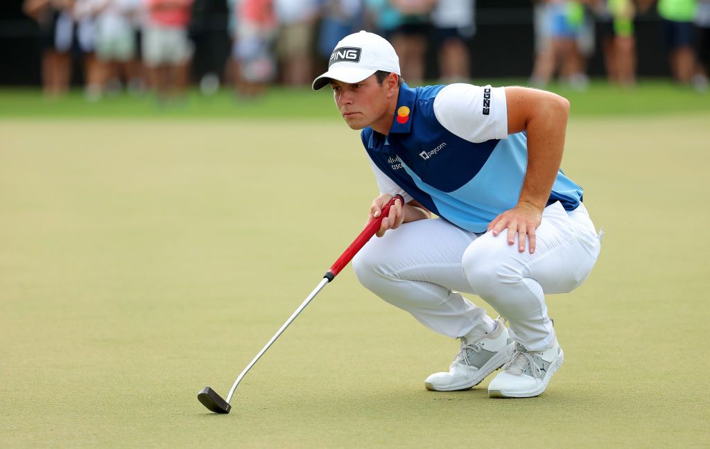 Viktor Hovland crouching behind a putt
