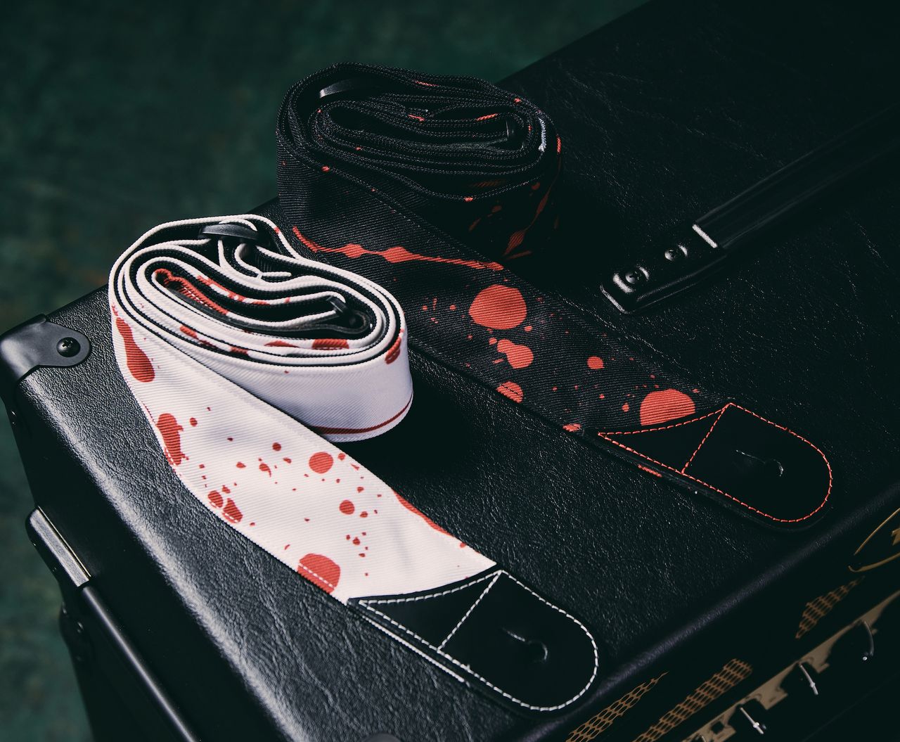 Two of Jackson's new guitar straps lie on a guitar amp