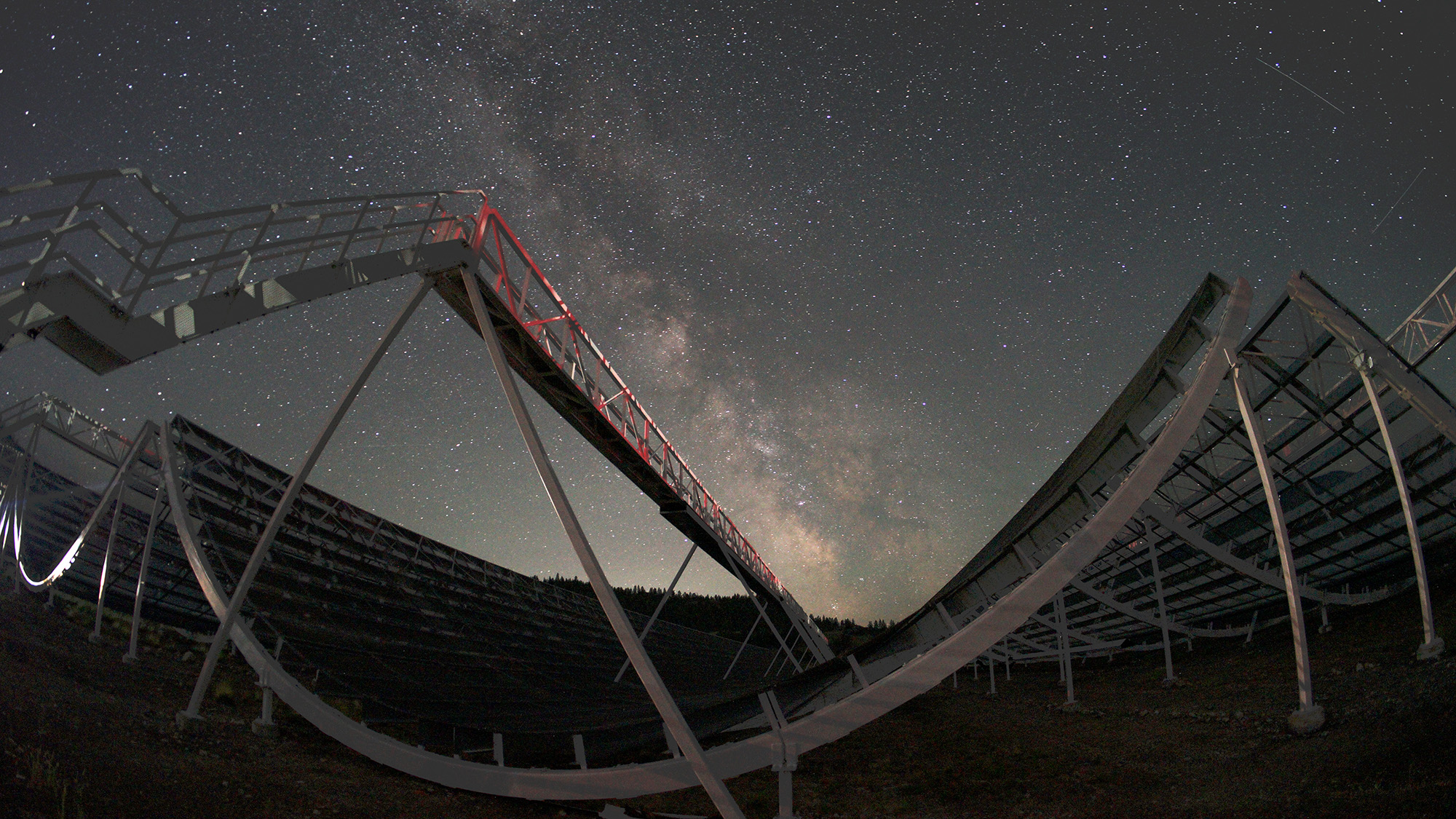 A panorama view of a telescope underneath a dark night sky.