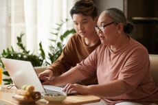 older woman working on a laptop with her grandson