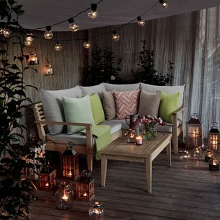festoon light with bulbs and cushions on wooden bench