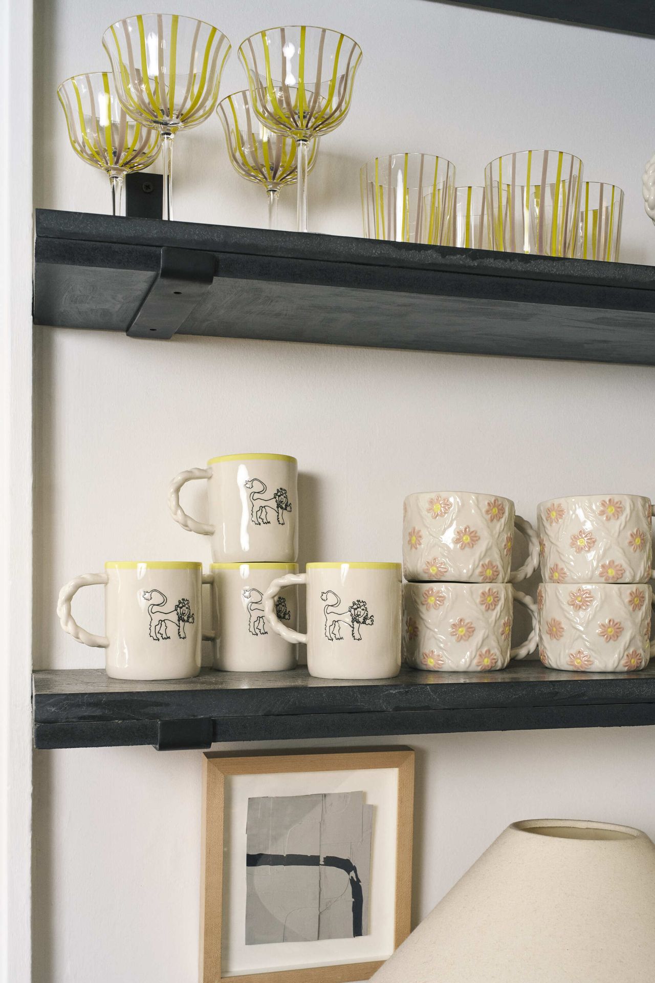 Image of two floating shelves. The first has ceramic mugs on it, and the top one has yellow striped glassware.