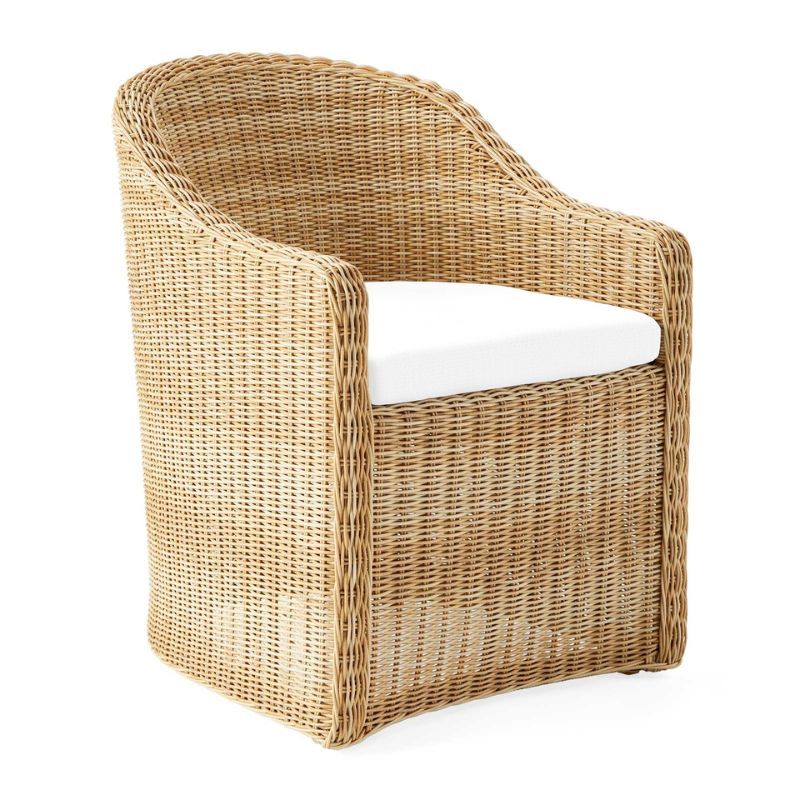 A Serena & Lily wicker curved back outdoor dining chair with a white seat cushion for the best outdoor furniture brands.