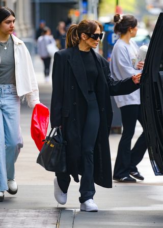Jennifer Lopez in New York City in April 2024, wearing all navy blue, including a navy blue jacket and Birkin bag