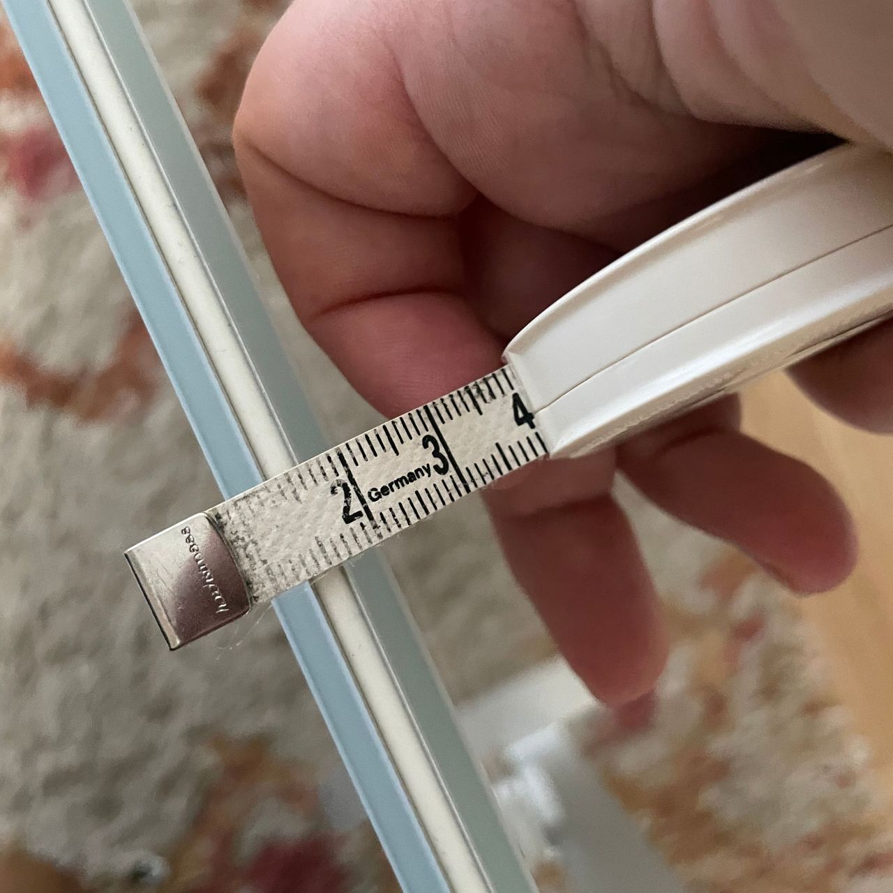 Hand holding a measuring tape, measuring the width of the Aeno Premium Eco Smart Heater