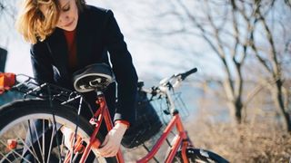 Woman using Dutch bike lock on the back wheel of a city bicycle