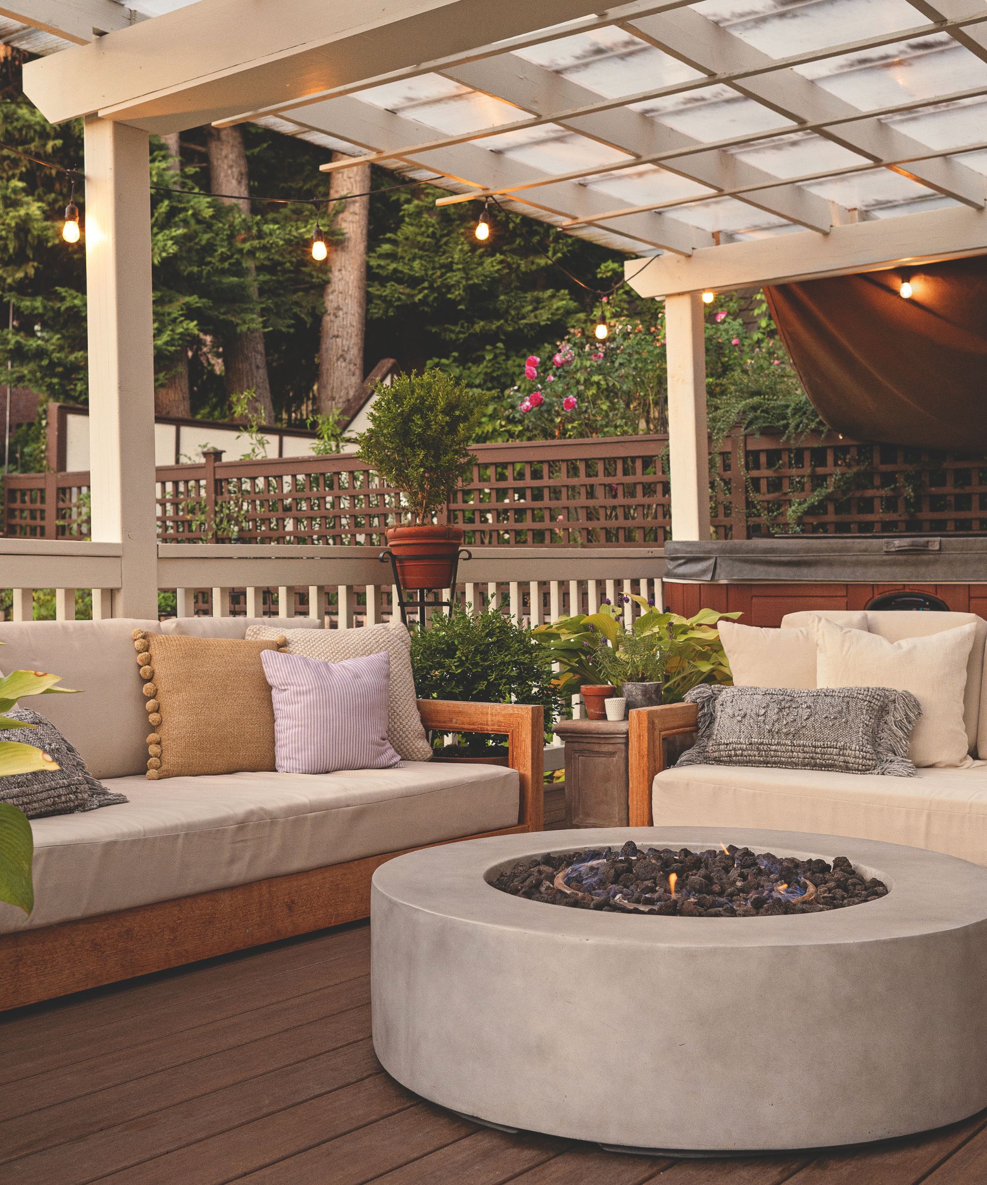 Covered patio with stone firepit and wooden outdoor sofas with cream cushions