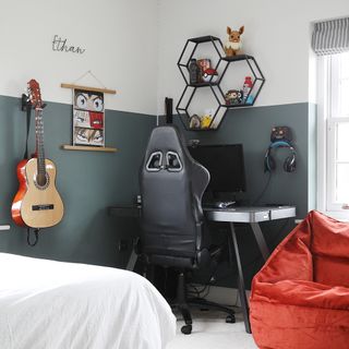 a teenager's bedroom with gaming chair, desktop computer and guitar on the wall