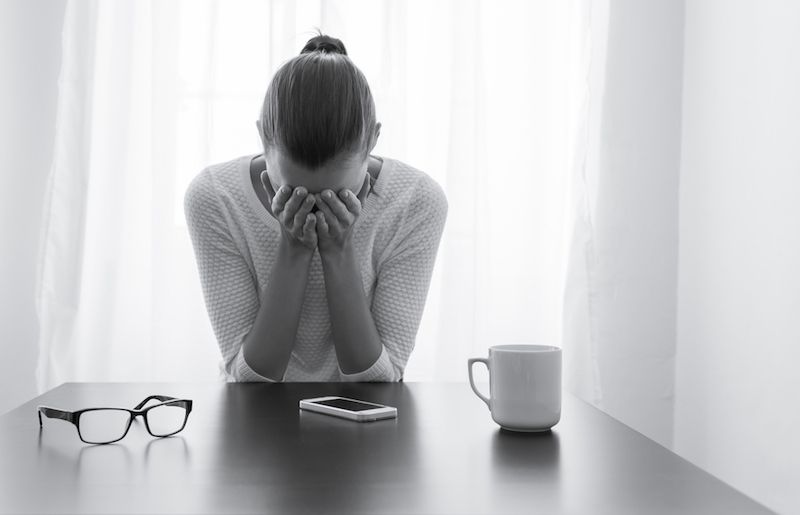 A woman holds her head in pain