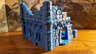 A 3D-printed ruin on a wooden table, in front of a D&D Dungeon Master screen