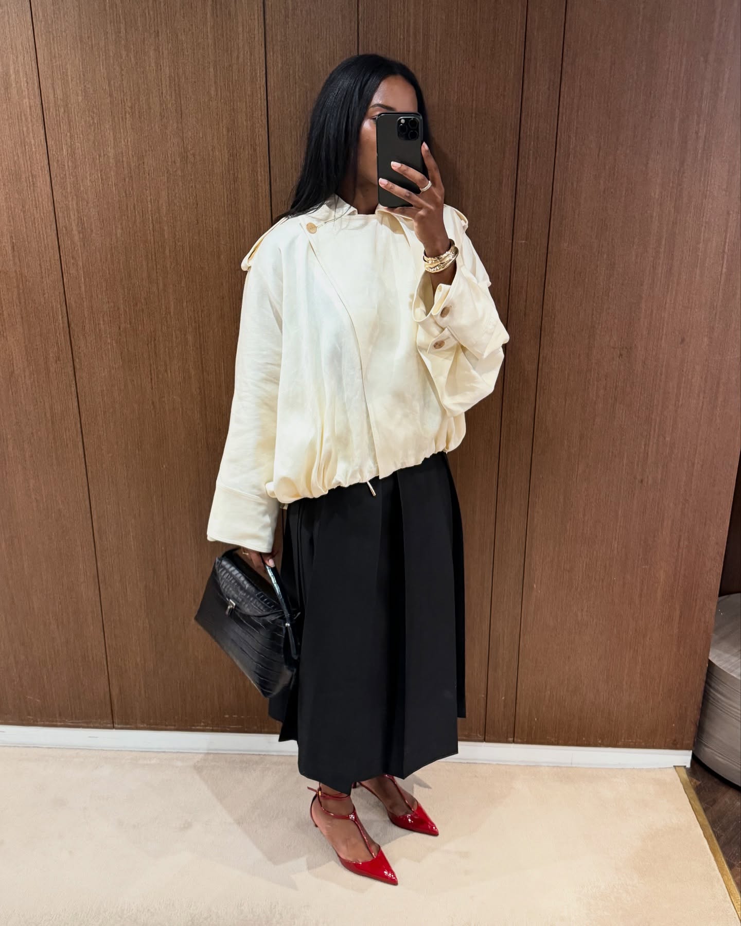 An image of @nlmarilyn wearing one of the best cape jacket with a black pleated maxi skirt and red pointed-toe heels.