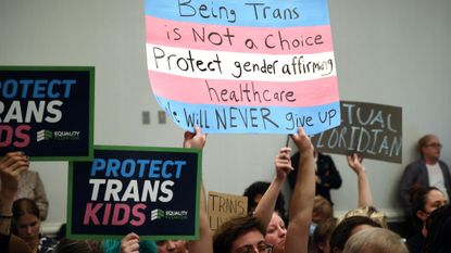 Protesters hold signs opposing Florida transgender treatment ban