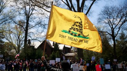A man holds a &lsquo;Don&rsquo;t Tread on Me&rsquo;&nbsp;flag during an Indiana protest in 2020.