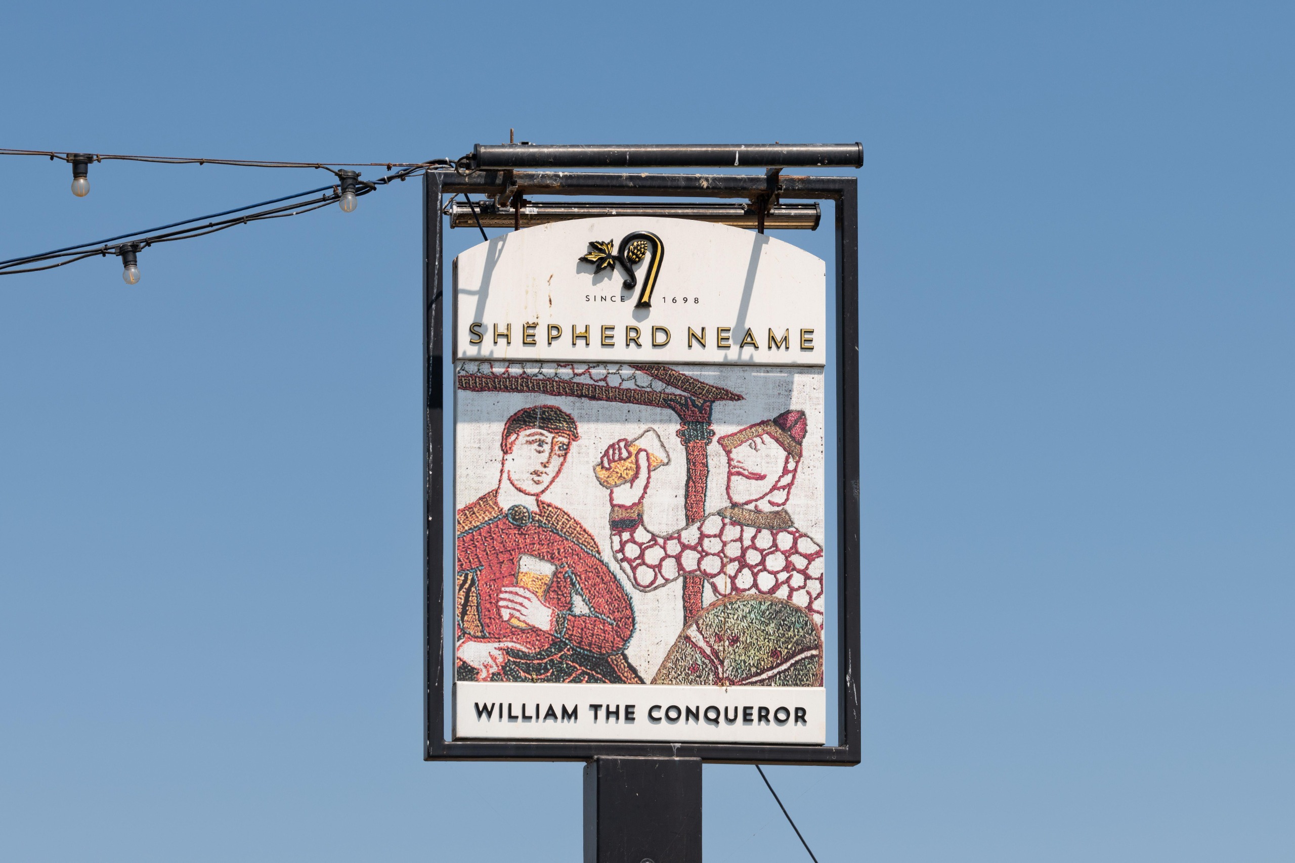 A pub sign, with a picture of the bayeux tapestry, that says William the Conqueror