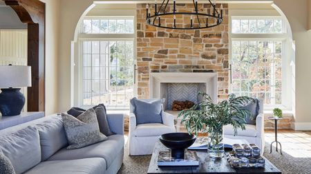 neutral living room with brick fireplace and gray and white sofas and armchairs