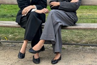 detail image of two women wearing black ballet flats and pantsuits