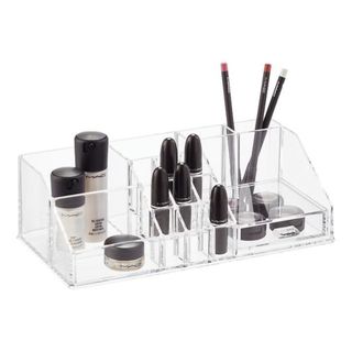 A shallow plastic makeup organizer features makeup brushes and makeup products