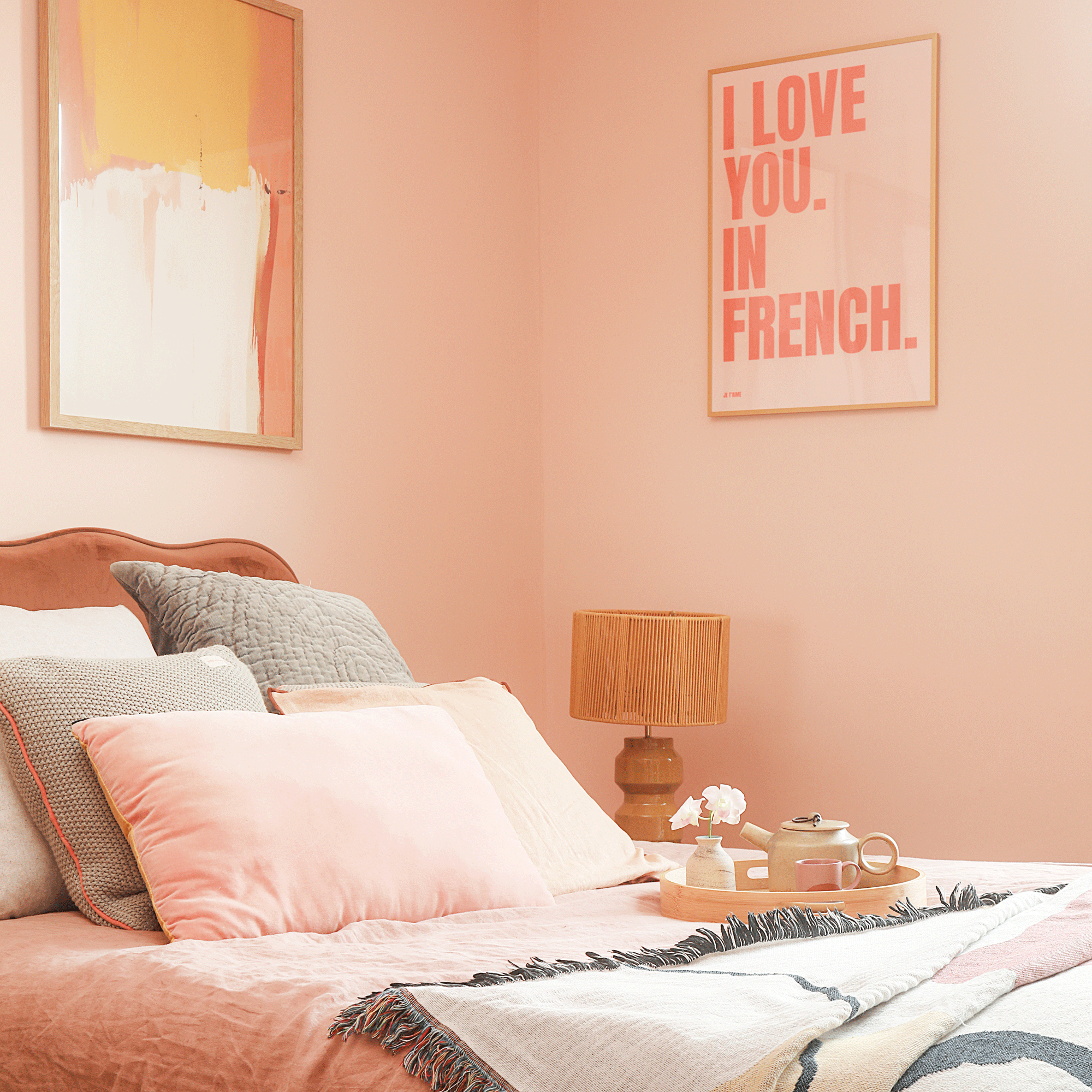 a bedroom in peach hues with peachy pink walls and pink bedding