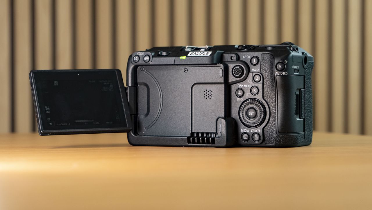 Canon EOS C50 on a wooden surface, view of the rear, screen flipped out