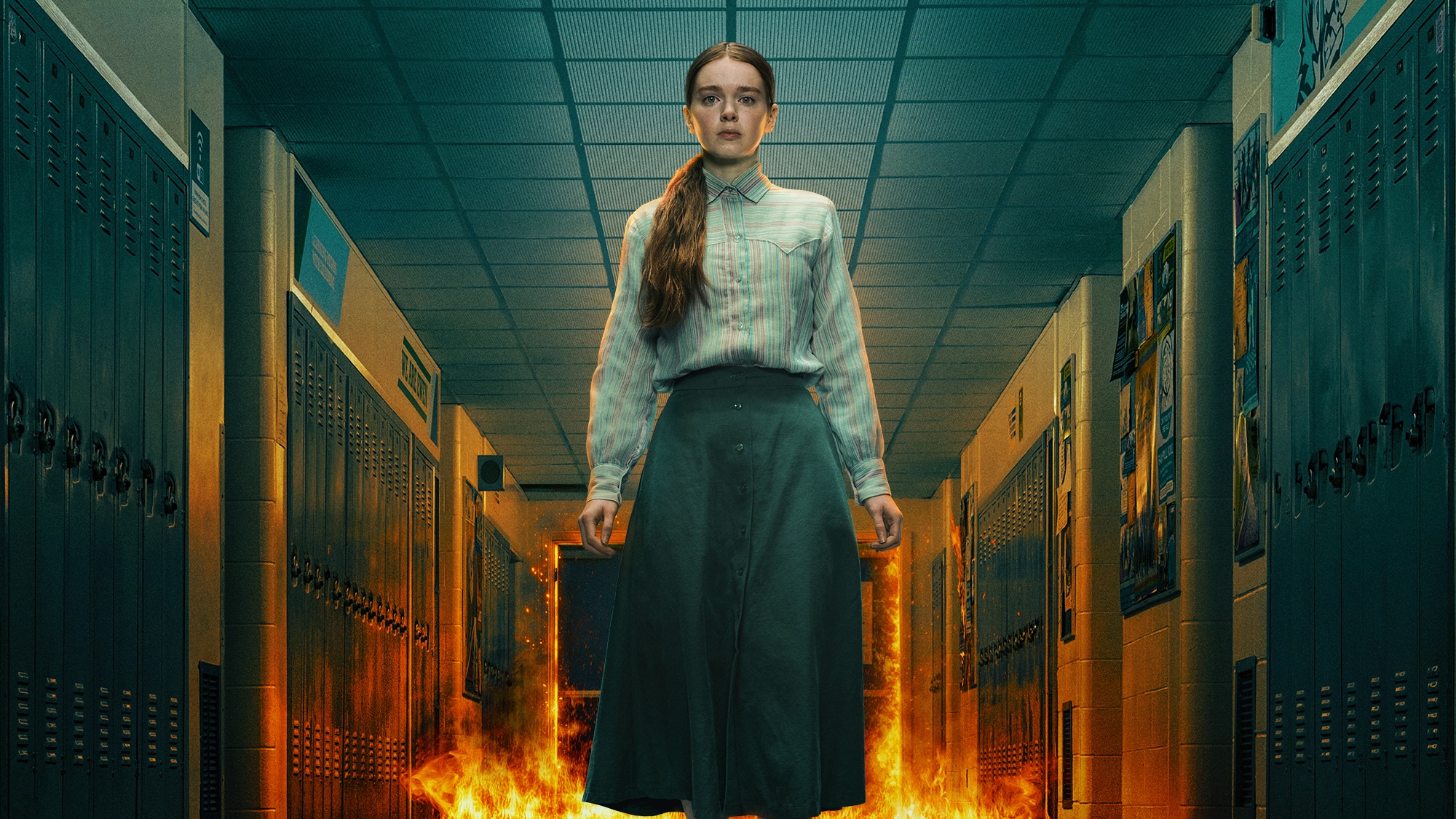 Carrie White in a striped button-down shirt and long skirt standing in high school hallway as a fire rages behind her in Carrie miniseries