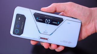 En hand håller upp en Asus ROG Phone 6 Pro i vitt med baksidan vänd mot kameran.