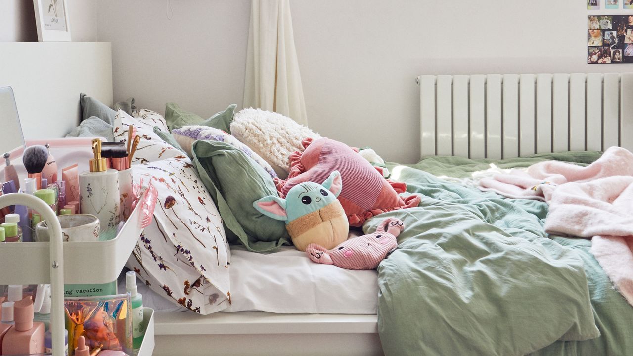 Bedroom with various plush toys and cushions on top of bed