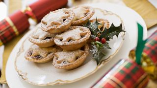 A plate of mince pies with a sprig of holly
