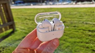 Samsung Galaxy Buds 3 Pro held in a hand outdoors