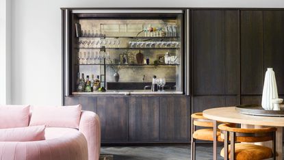 A home bar in a cupboard in a room with dining table and sofas