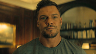 Alan Ritchson looking forward in Reacher. 