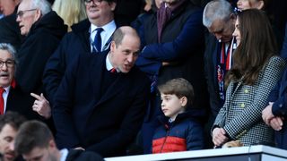 Prince William speaks to Prince George, who is standing next to the Princess of Wales, prior to the Guinness Six Nations Rugby match between England and Wales at Twickenham Stadium on February 26, 2022