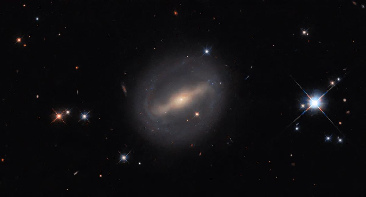 A hazy and glowing galaxy with a slight ring around it in space.