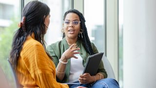 Therapist talking to a woman, holding a notepad