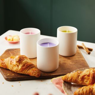 Scented candles on wooden chopping board and pastries