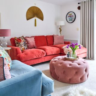 Colourful living room, red sofa and cushions, pink pouffe