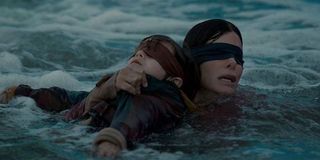 Sandra Bullock as a blindfolded Malorie holding Julian Edwards as Boy in Bird Box