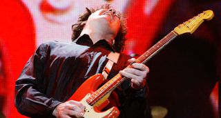 Gary Moore plays a note and feels it on his red Fender Strat, live at London's Wembley Arena in 2004.