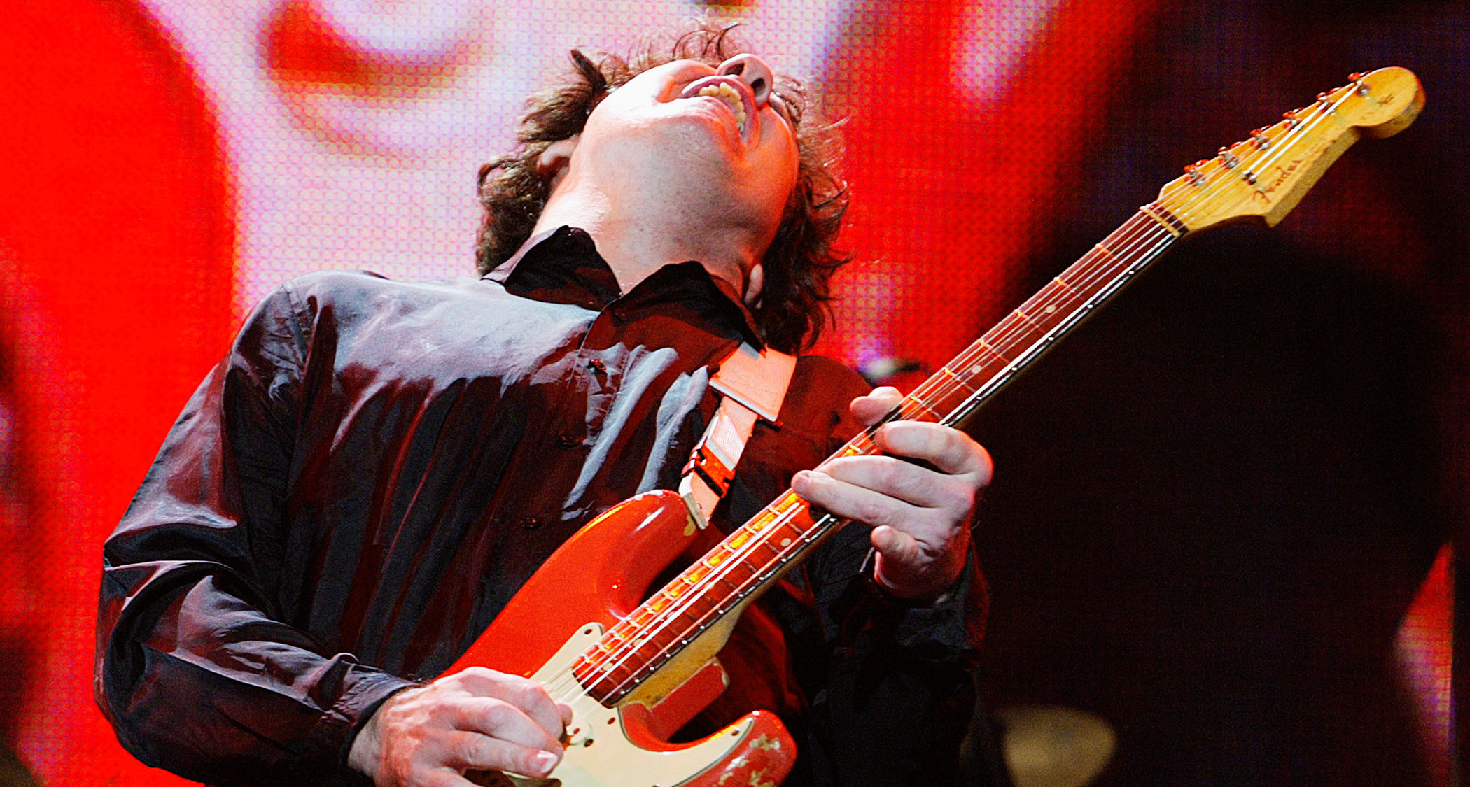 Gary Moore plays a note and feels it on his red Fender Strat, live at London&#039;s Wembley Arena in 2004.