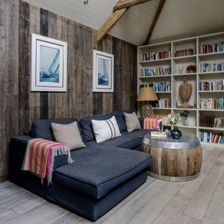 cornish dream home living room with wood wall panelling drum coffee table and library shelving