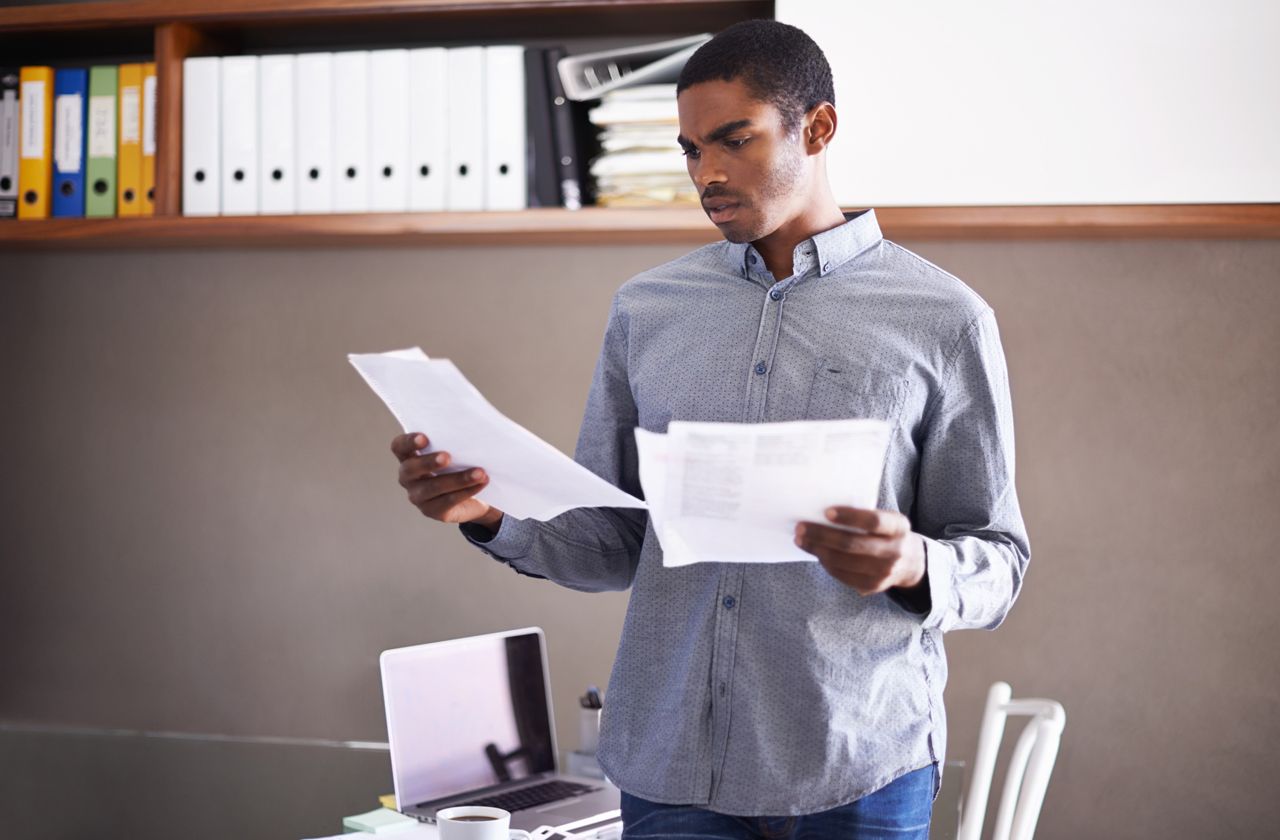 Shot of a handsome young businessman looking over some paperwork in his home officehttp://195.154.178.81/DATA/i_collage/pi/shoots/783543.jpg