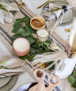A Christmas table with candles, leaves, plates, and dried flowers