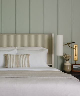 Sage green, panelled wall, headboard, brass side light