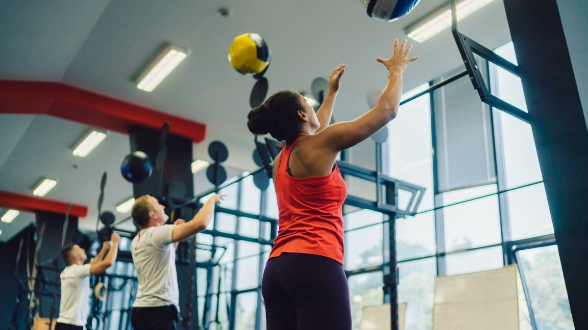 People performing medicine ball squat throws