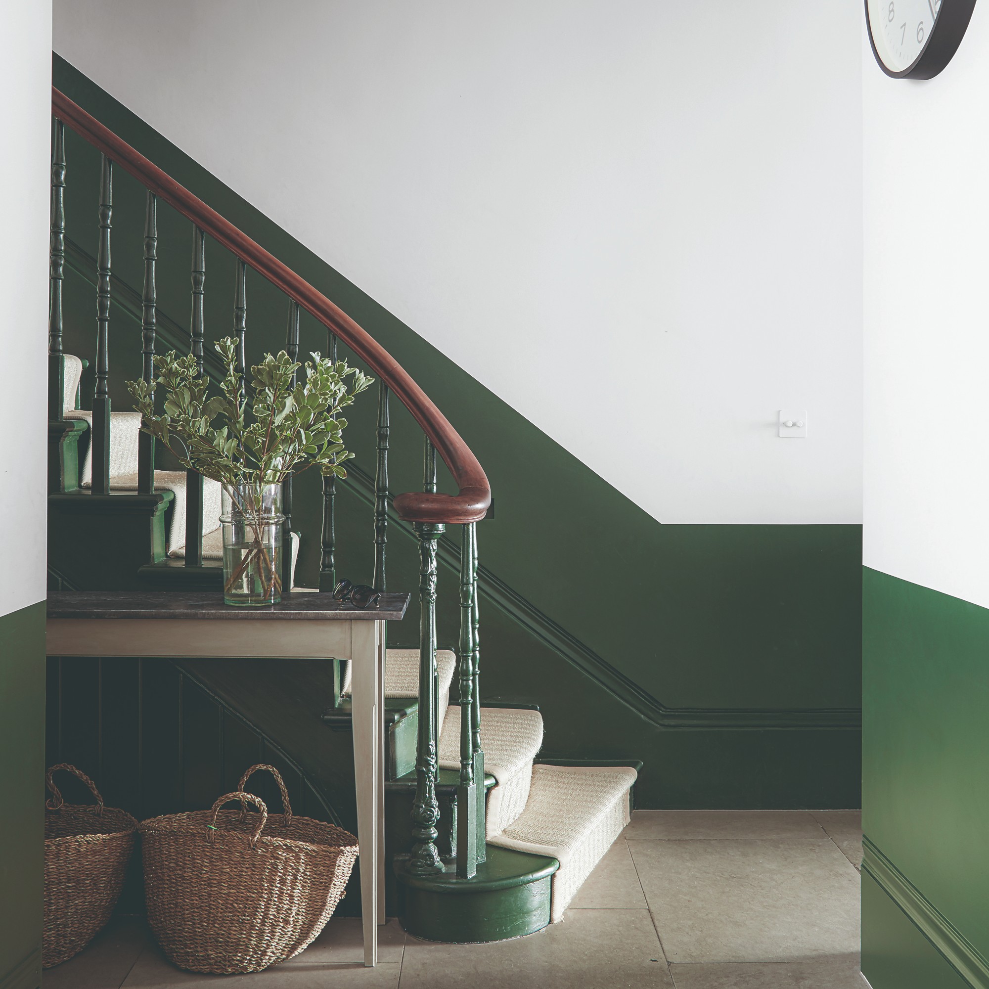 A hallway with two-tone walls in white and forest green with a staircase
