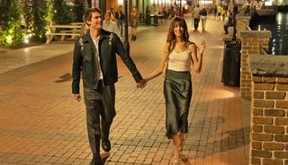 Anne Hathaway and Nicholas Galitzine walking down a street holding hands in 'The Idea of You'