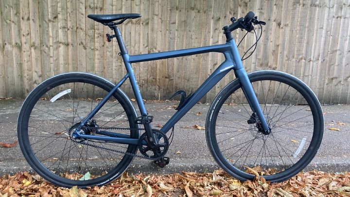 A metallic blue Boardman URB 8.9 hybrid bike in leafy urban environment