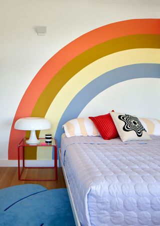 A bedroom with a rainbow painted behind the bed