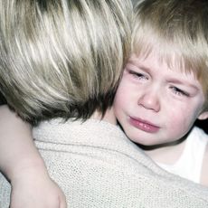 A child crying in parent's arms.
